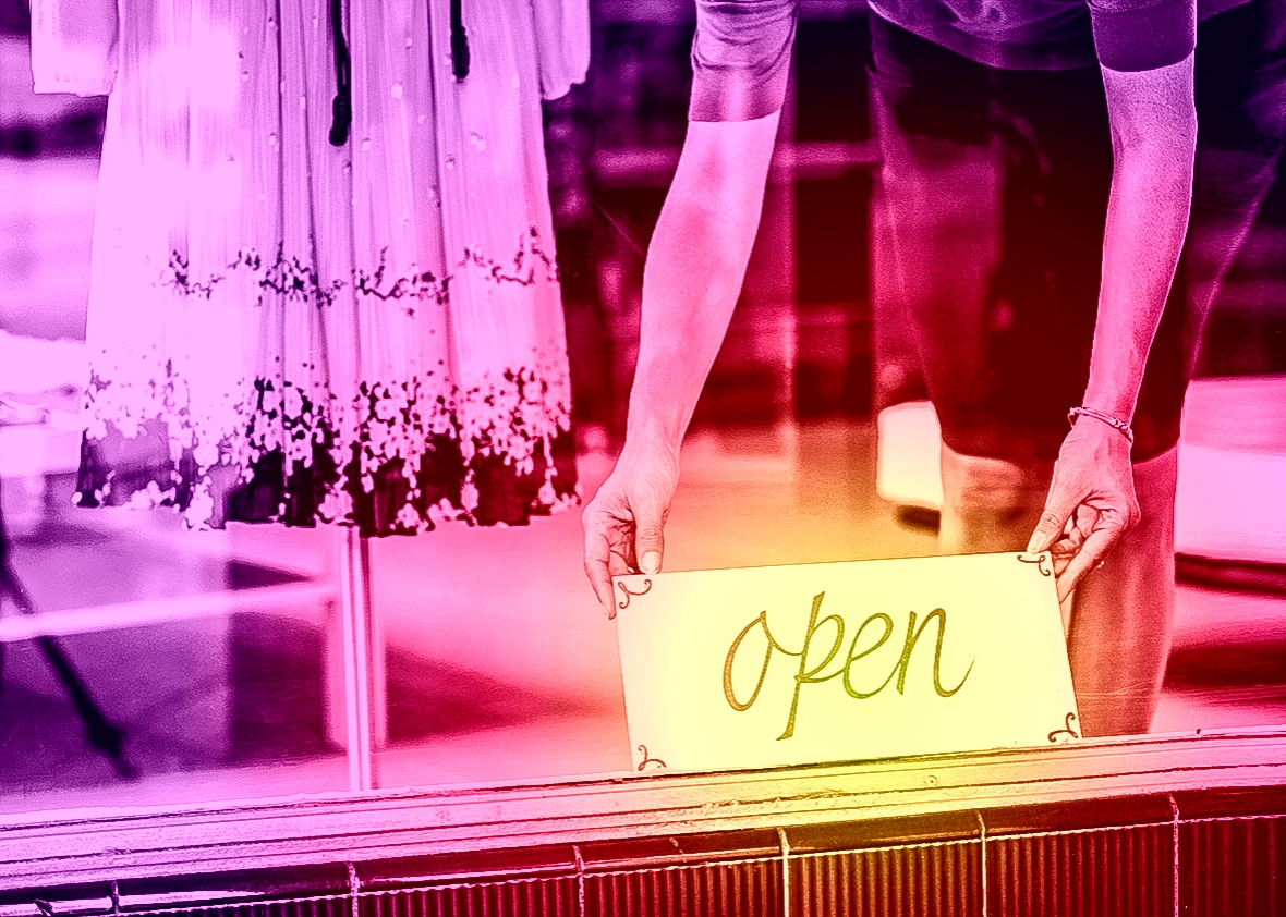 Boutique salesperson placing open sign on window.