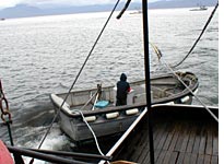 The skiff rounds Wind Walker's stern