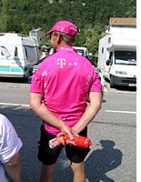 A soigneur (caregiver) waits to hand drinks to passing riders