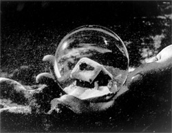Close up of a hand holding a snowglobe containing a tiny cabin in Citizen Kane. Click image to expand.