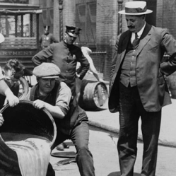 New York City Deputy Police Commissioner John A. Leach, right, watching agents pour liquor into sewer following a raid. 