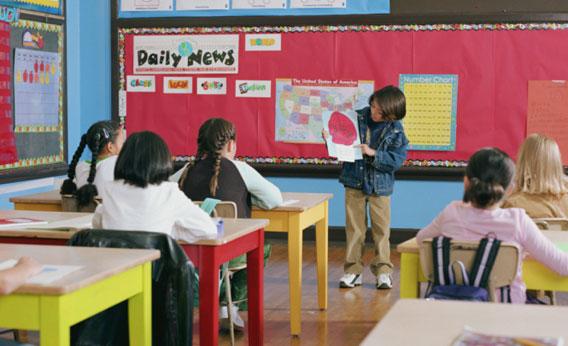 Boy giving presentation at the front of the classroom.