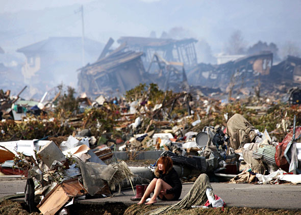 A woman cries while sitting on a road amid the destroyed city of Natori, Miyagi Prefecture in northern Japan March 13, 2011