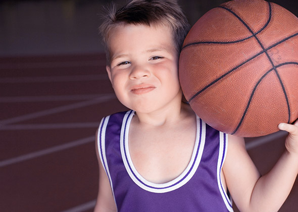 Boy in basketball uniform holding basketball.