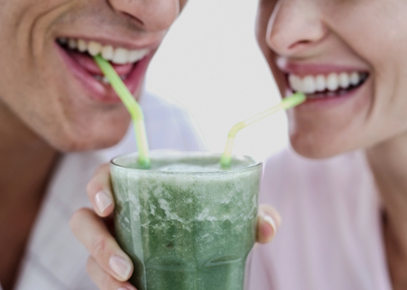 Close-up of a young couple sharing a glass of juice with straws