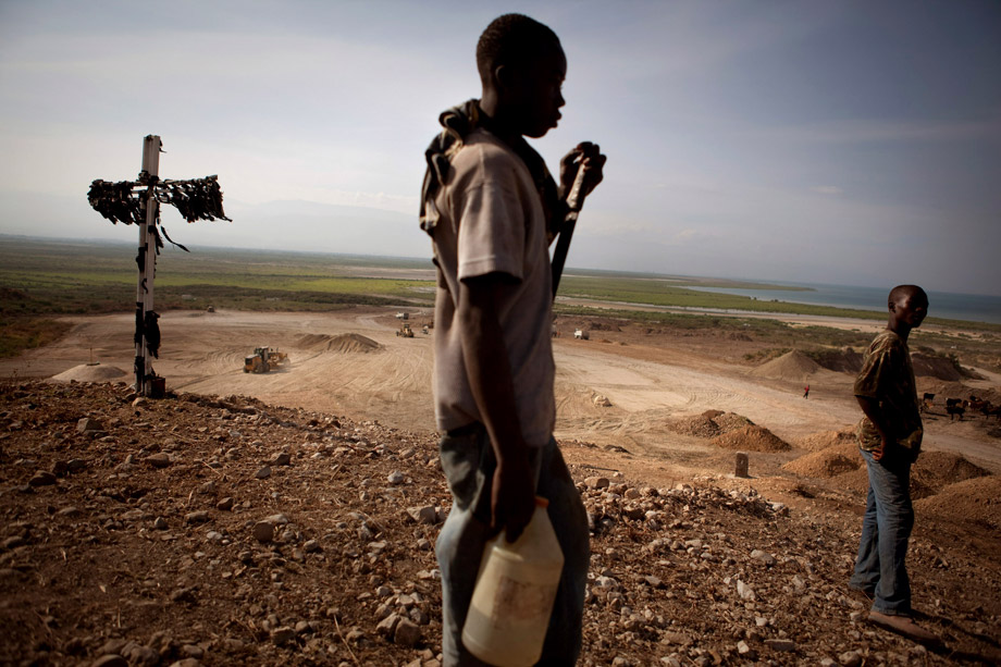 Boys on their way to fill water jugs pause near a cross adorned with black cloth on a hill overlooking a burial site outside Port-au-Prince, Jan. 10, 2011. Mass graves of victims of the Jan. 12, 2010, earthquake and the cholera epidemic are found buried at the site.