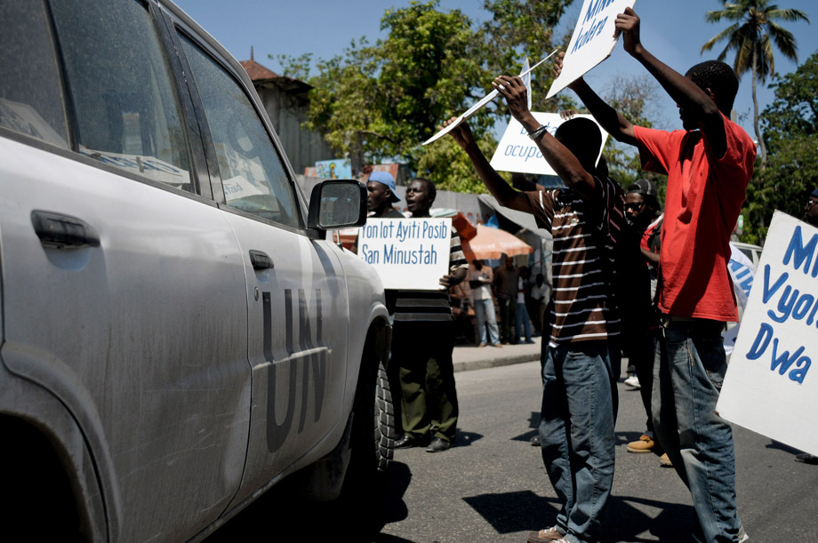 Demonstrators holding placards surround a U.N. vehicle during a protest in Port-au-Prince, July 28, 2011. Protesters said they want justice from the United Nations Stabilization Mission in Haiti (MINUSTAH) after a study by the U.S. Centers for Disease Control and Prevention (CDC) showed that a unit from Nepal might be responsible for bringing cholera into the country, which has killed more than 5,500 people so far. 