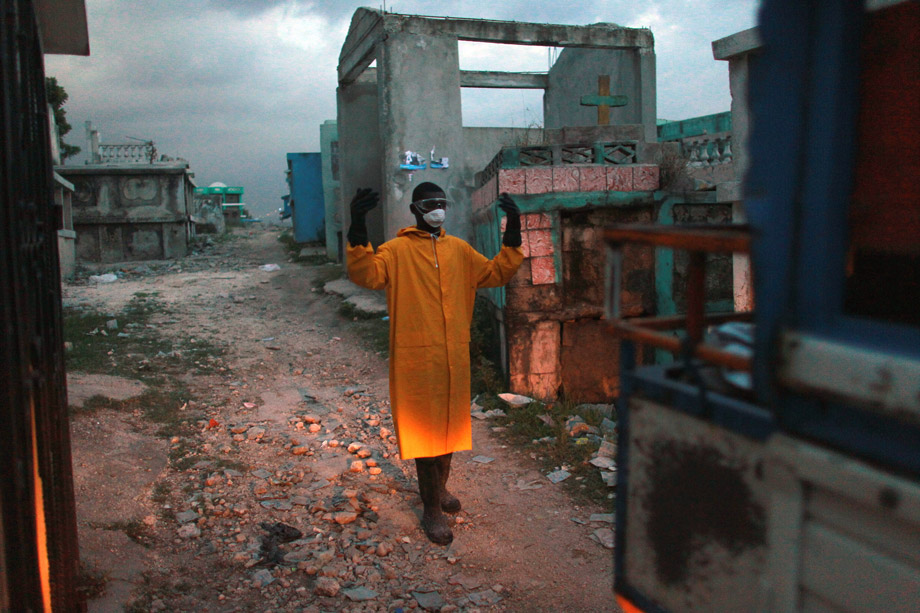 A member of a Haitian Ministry of Health body collection team directs a truck as it backs up to drop off two victims of the cholera outbreak covered in plastic bags at a cemetery on Nov. 16, 2010, in Port-au-Prince, Haiti. T