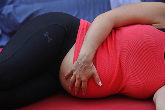 A pregnant woman touches her stomach as people practice yoga on the morning of the summer solstice in New York's Times Square June 20, 2012. 