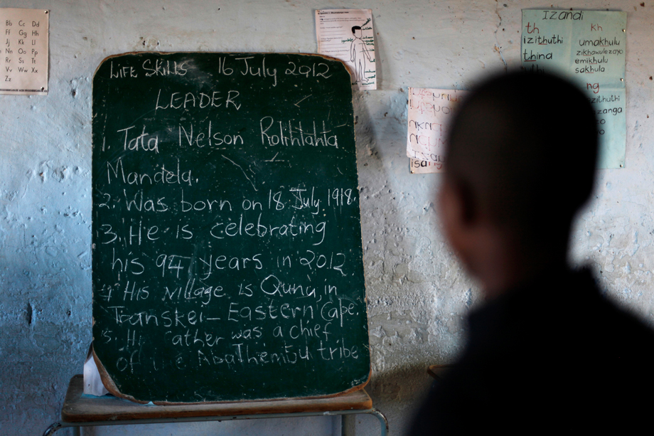 School children read the history of former South African President Nelson Mandela written on a chalkboard, ahead of the opening of a container library by the Bill Clinton foundation in celebration of Mandela day, at a school in Qunu, July 17, 2012. 