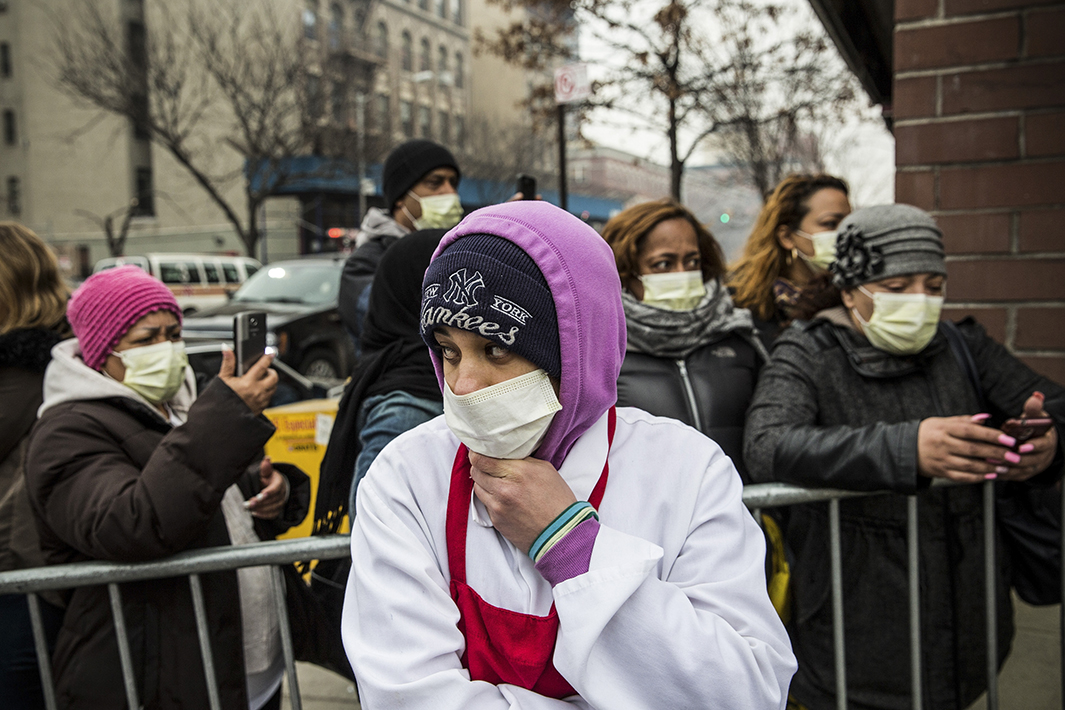 Onlookers wear face masks as they watch from behind a barricade. 