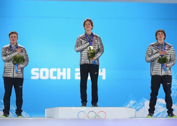 Silver medalist Gus Kenworthy of the United States, gold medalist Joss Christensen of the United States and bronze medalist Nicholas Goepper of the United States pose during the National Anthem during the medal ceremony for the Freestyle Skiing Men's Ski Slopestyle on day six of the Sochi 2014 Winter Olympics.