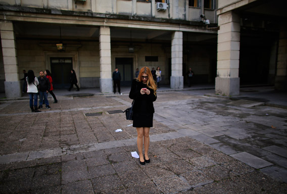 A woman holds a cell phone as she stands next to a courthouse in the Andalusian capital of Seville February 20, 2013.