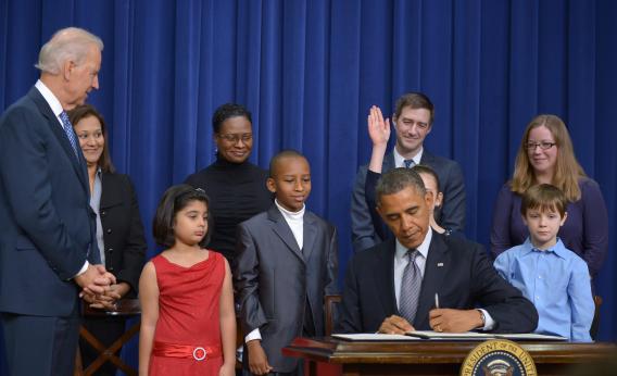 President Barack Obama signs executive actions to curb gun violence as Vice President Joe Biden and invited guests look on, Jan. 16, 2013, in the South Court Auditorium of the Eisenhower Executive Office Building