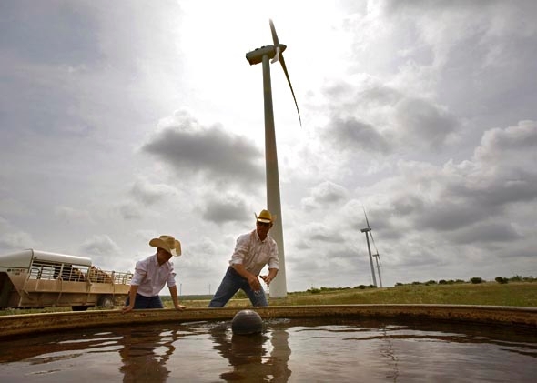 Clifton Brandon, 43, and his son, Teagan, 10 years, clean a water tank for their 300-head of black angus cattle on the Lone Star Wind Farm 17 miles north of Abilene, Texas June 9, 2007. 