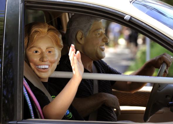 103179810-tourists-in-bill-and-hillary-clinton-masks-drive