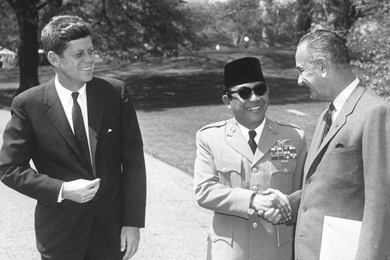 President of Indonesia Sukarno (center) shakes hands with US Vice President Lyndon Johnson as President John F. Kennedy smiles.