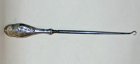 An early 20th century art nouveau steel button hook with a sterling silver handle.