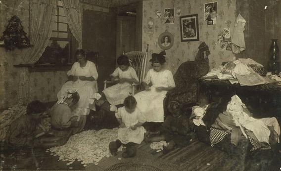 Stringing buttons from button molds in a crowded Massachusetts home, September 1912.