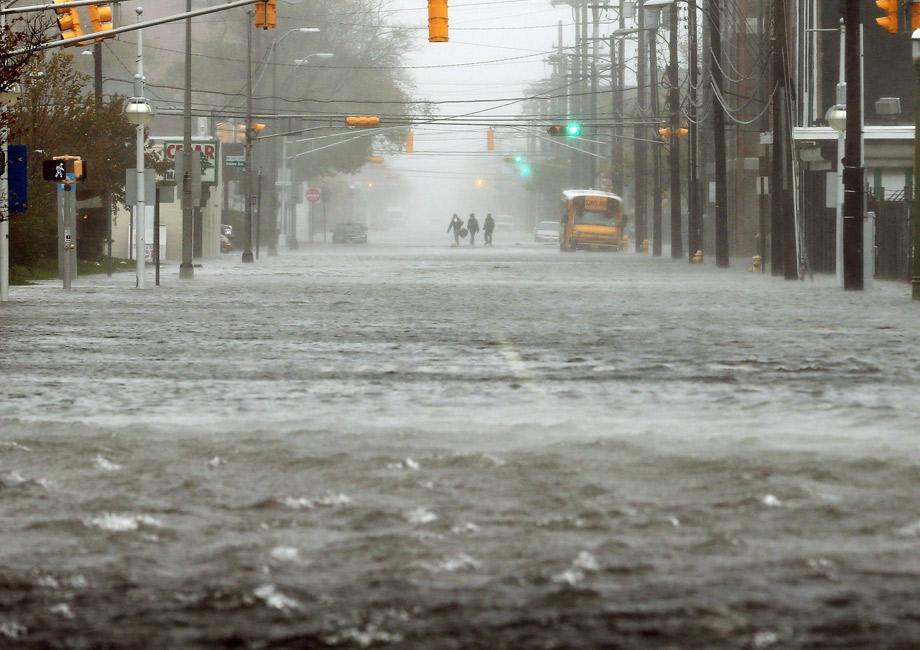 People walk down a flooded street as Hurricane Sandy moves up the coast on Monday in Atlantic City, New Jersey. 