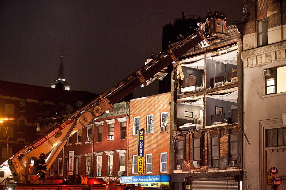 Fire fighters evaluate the scene of an apartment building which had the front wall collapse due to Hurricane Sandy on October 29, 2012 in New York.