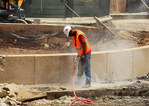 A worker at a construction site in Rockville, Maryland, breaks up concrete with a jackhammer, creating a cloud of silica dust. 
