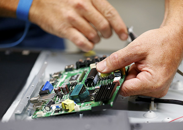 A worker lines up the motherboard as he assembles a 32-inch TV.