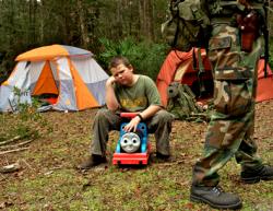 A young boy sits on a child's toy and sulks because his sister got to carry the rifle that he wanted to carry as members of the North Florida Survival Group gather for a field training exercise in Old Town, Florida, December 8, 2012.