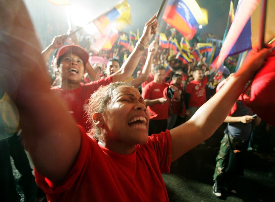 Supporters of Venezuelan President Hugo Chavez celebrate in the rain in front of the Miraflores Palace as Chavez gives a speech from the balcony after official election results gave him a victory by a wide margin in Caracas December 3, 2006. The anti-U.S. Venezuelan president claimed victory with a cry of &quot;long live the revolution&quot; as official results showed him heading for a landslide re-election win on Sunday.  
