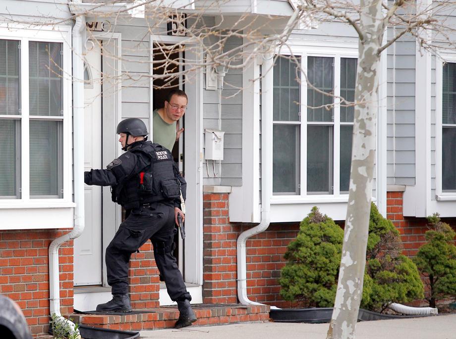 A man looks out of his door as a SWAT team member knocks on his neighbors door as they search for the remaining suspect in the Boston Marathon bombings in Watertown, Massachusetts April 19, 2013. Boston Police Commissioner Ed Davis warned the entire city of Boston to &quot;shelter-in-place&quot; on Friday as authorities pressed a manhunt for the second suspect in the Boston Marathon bombings. 