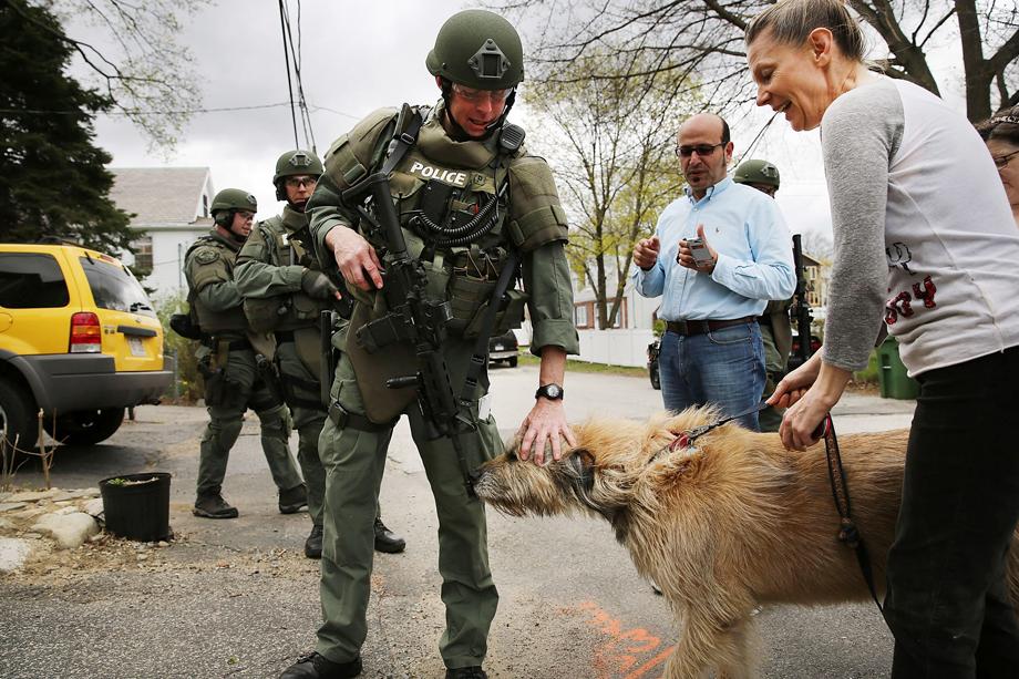 A SWAT team member pets a dog as they conduct a door-to-door search for 19-year-old Boston Marathon bombing suspect Dzhokhar A. Tsarnaev on April 19, 2013 in Watertown, Massachusetts.