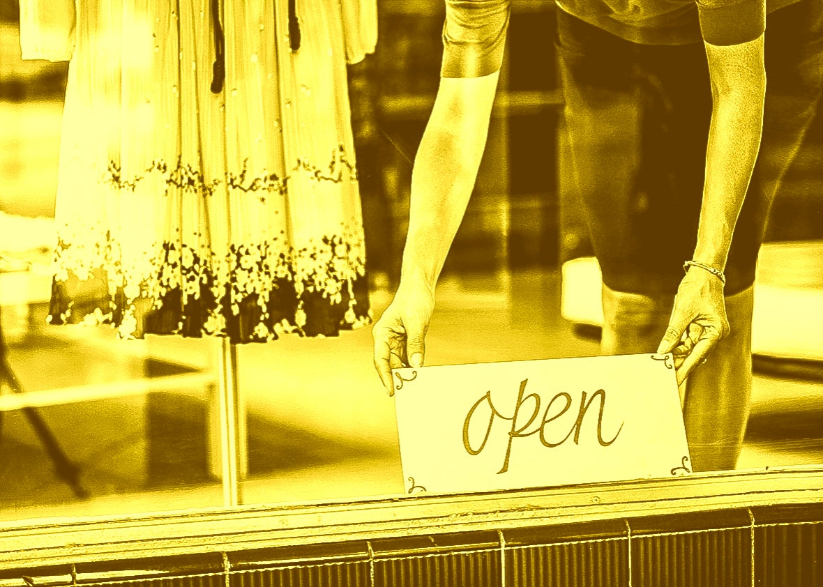 Boutique salesperson placing open sign on window.