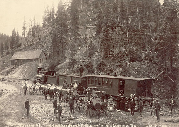 Buggies, wagons, and horse teams by a Silverton Railroad passenger car in Red Mountain Town, Ouray County, Colorado, 1888. 