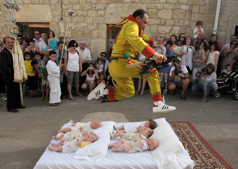 117374793-man-representing-the-devil-leaps-over-babies-during-the
