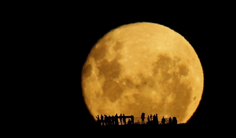 people silhouetted by the Moon