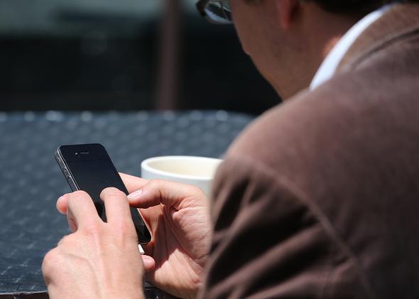 169973293-man-uses-a-smartphone-as-he-sits-in-union-square-on