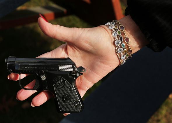 158638982-woman-holds-a-beretta-pistol-at-a-gun-buyback-event-at 158638982-woman-holds-a-beretta-pistol-at-a-gun-buyback-event-at